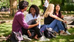 International students sit together on a lawn on campus.