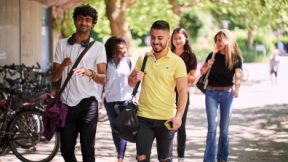 Internationale Studierende gehen gemeinsam durch einen Park.