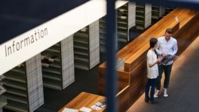 View from above of two students talking in the library.